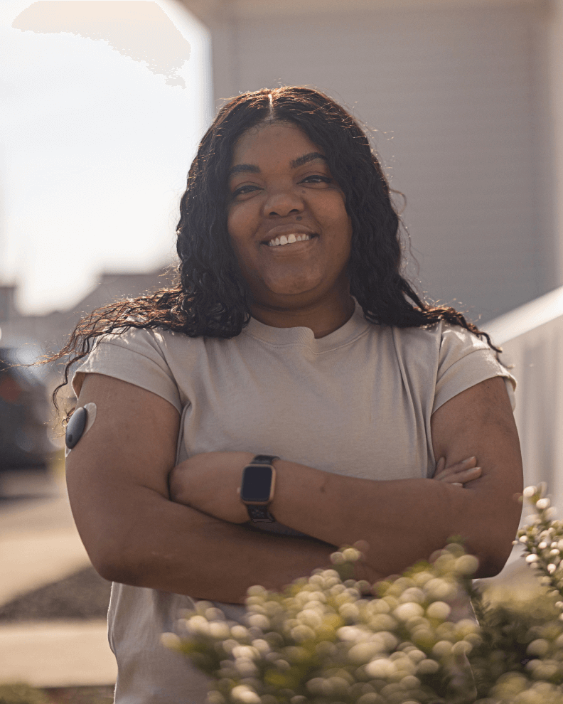 Mary, an Eversense user since 2020, standing outdoors with her CGM transmitter on her arm